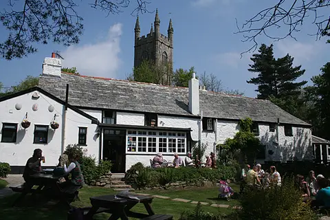 The Crown Inn in sunshine with drinkers at tables outside the whitewashed front