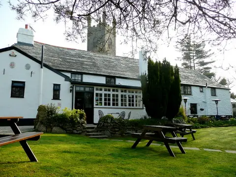 The Crown Inn from its garden, white walls and slate roof under the church tower