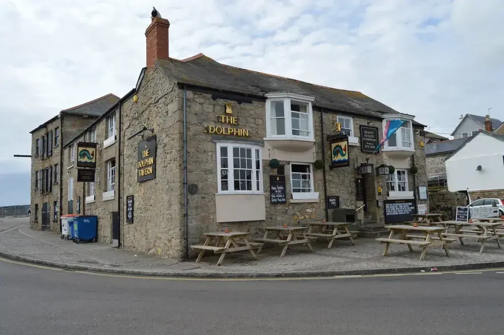 Granite corner tavern with bay windows, gold lettering and picnic benches on the quayside