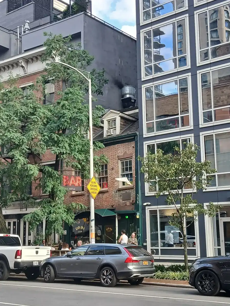 The Ear Inn’s small brick house on Spring Street, BAR in red neon, new blocks either side