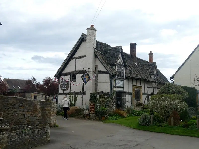 The black-and-white timbered front of the Fleece Inn with its painted Mitchells & Butlers ales sign