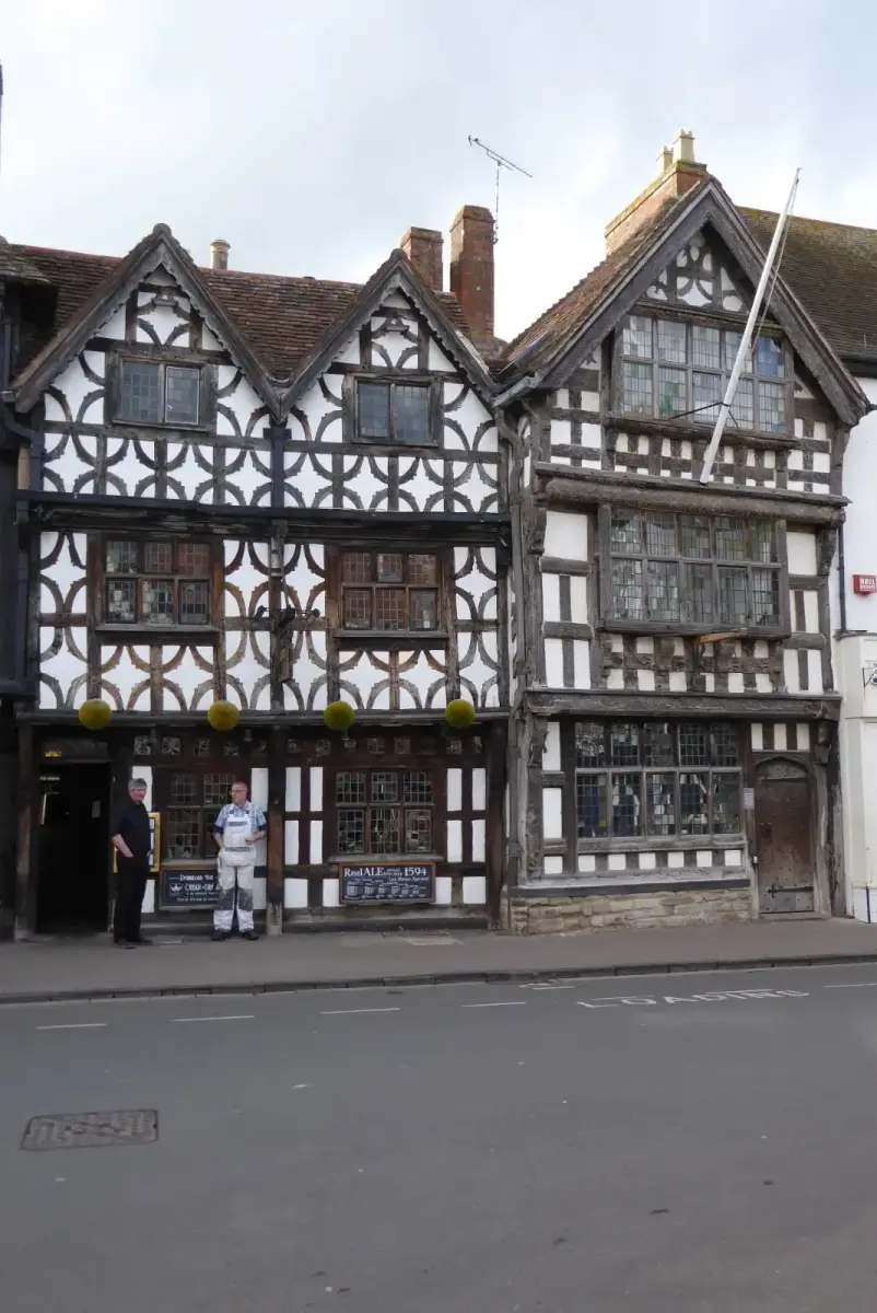 Two timber-framed houses with decorative curved bracing and gables, on a town street