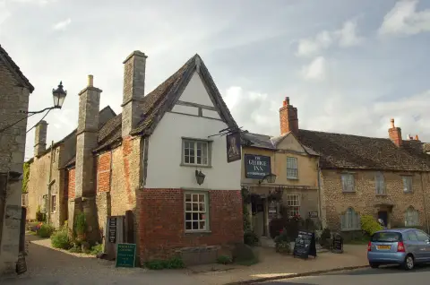 Gabled inn with exposed timber in the apex over a brick lower storey, hanging sign on an iron bracket