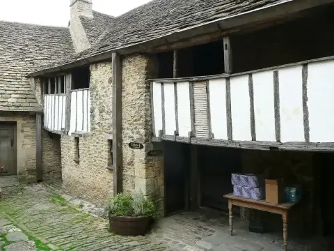 Timber-framed open gallery on stone piers running round a cobbled inn courtyard