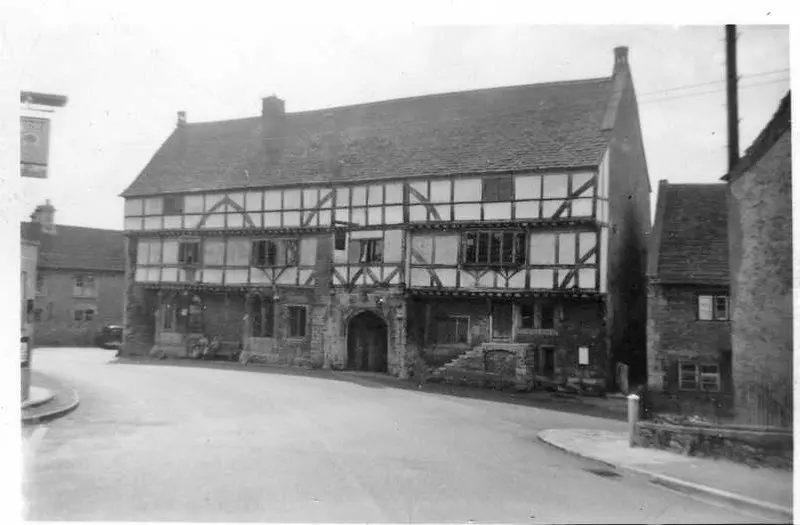 The George Inn's timber-framed upper floors and stone archway seen from the road junction in 1955