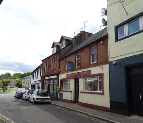 The white frontage of the Globe Inn in Dumfries with its hanging sign over the pavement