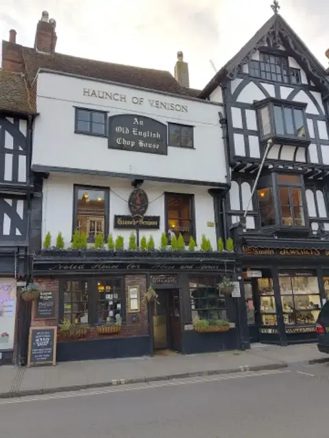 White-painted three-storey front lettered Haunch of Venison above a board reading An Old English Chop House