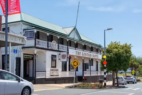 White weatherboard hotel with a green roof, lace-ironwork verandah and gold lettered sign