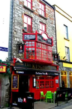 Tall limestone building with a bright red timber shopfront and oriel window on a narrow street