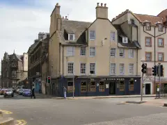 Four-storey harled tenement on a Leith corner, dark blue ground floor lettered with the pub name and number 36