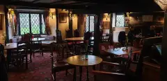 Low-beamed bar room with leaded bay windows, dark timbers and a scatter of wooden tables