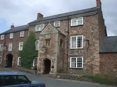 Red sandstone inn with a gabled stone porch, ivy on the wall and a carriage arch to the left