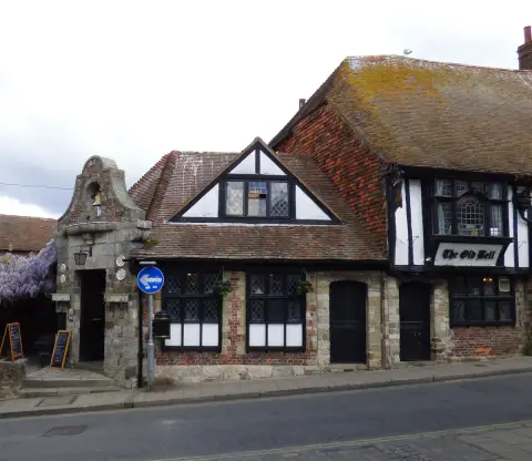 Timber-framed and stone inn with leaded windows and a mossy tiled roof, bell gable to the left