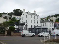 The white three-storey Old Court House Inn facing St Aubin's harbour, with its name on the front and a smaller Gothic-windowed wing