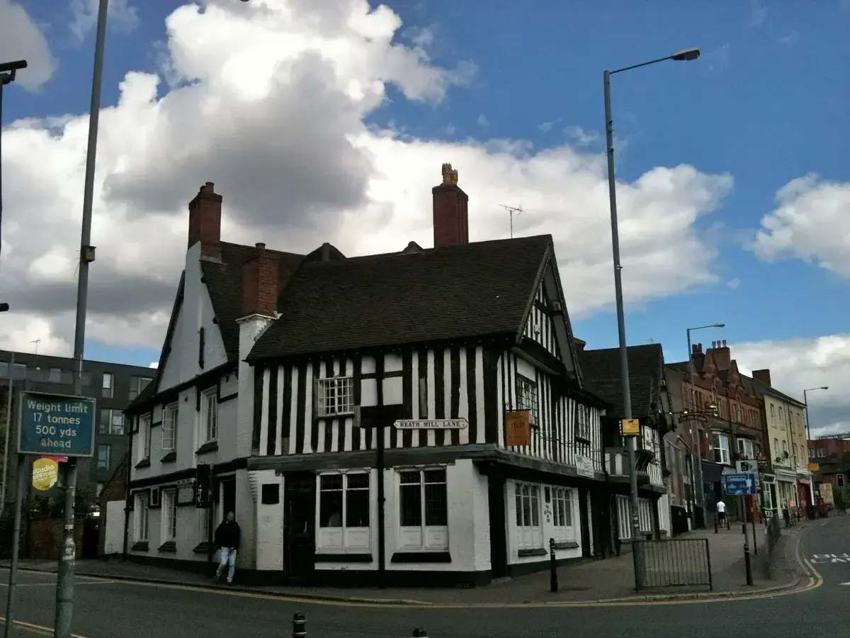 Timber-framed corner pub with close studding, jettied first floor and two brick chimneys