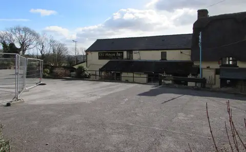 The long whitewashed range of the Old House Inn, thatch at one end, seen across its car park