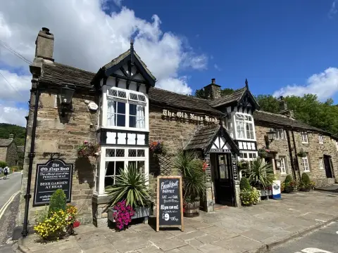 Stone pub in strong sun with a black board reading the official start of the Pennine Way