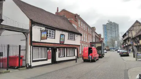 Spon Street with the low timber-framed pub on the left and a tower block in the distance