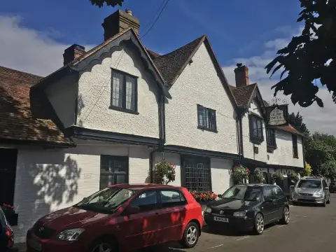 Two white gabled bays with dark bargeboards and leaded windows above a row of parked cars