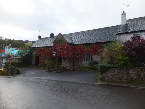 The Oxenham Arms under autumn creeper, granite walls and slate roofs in low sun