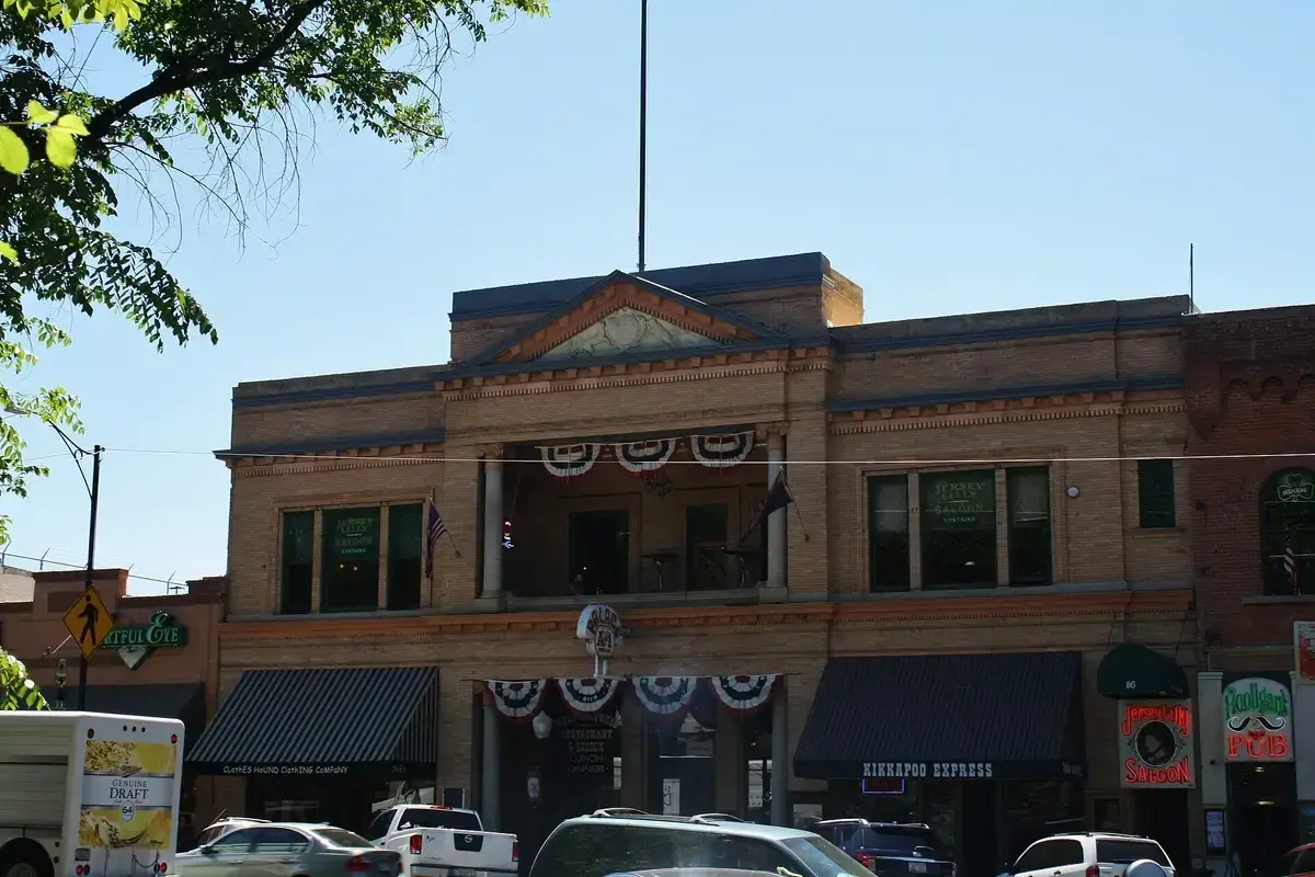 Buff-brick building with a pedimented parapet, arched loggia and bunting, on Whiskey Row