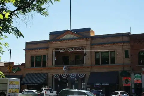 Buff-brick building with a pedimented parapet, arched loggia and bunting, on Whiskey Row