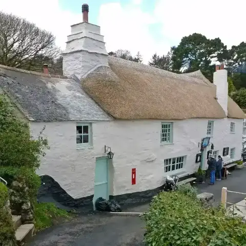 Whitewashed thatched inn with a broad stone chimney, beside a lane at the head of a creek
