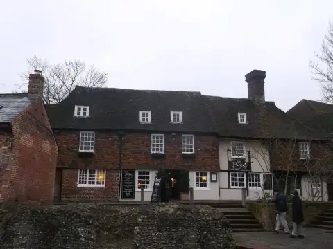 Brick and timber pub with dormer windows and a tiled roof, above a flint city wall