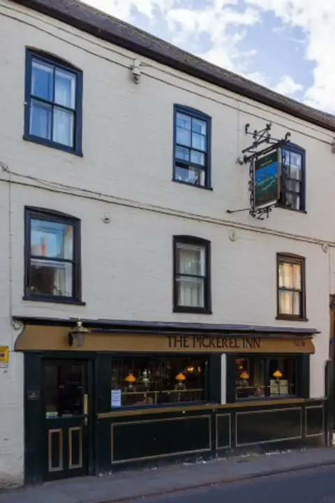 Three-storey white-painted inn with a dark green shopfront and lettered fascia on a street corner