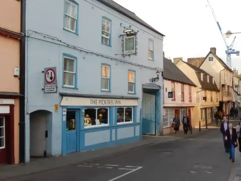 The same inn painted pale blue, with its carriage gate, seen along Magdalene Street
