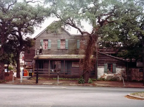Clapboard house behind live oaks, its porch and shuttered windows, photographed in 1984