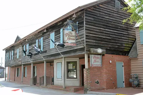 Long weatherboard and brick range with blue shutters, jolly roger flags and a Pirates' House sign