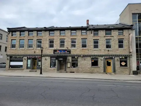 Three-storey limestone building with a black awning and lettered sign along a wide street