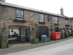 Stone rear range of the inn with an arched carriage entry, blackboards and a carved wooden bear
