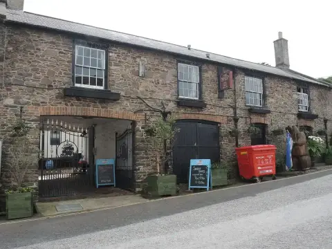 Stone rear range of the inn with an arched carriage entry, blackboards and a carved wooden bear