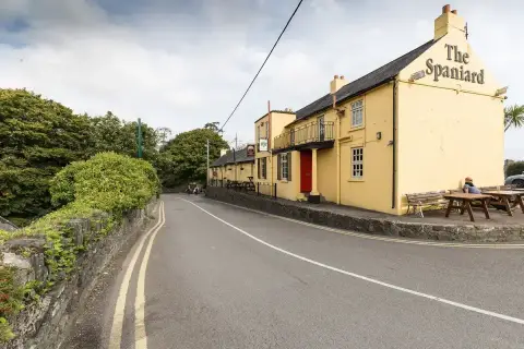 The Spaniard at Kinsale, its name in black letters across the yellow gable, benches outside