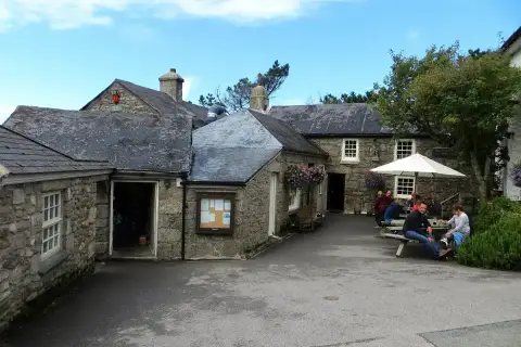 Granite buildings around the pub yard with open doors, a noticeboard and drinkers at tables