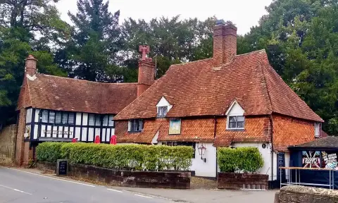 The same pub from further along the road, deep tiled roofs stepping down to a rendered wing