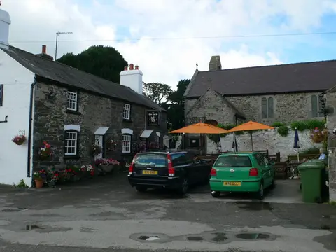 The White Lion Inn at the roadside with St Elian’s church beyond and cars parked in front