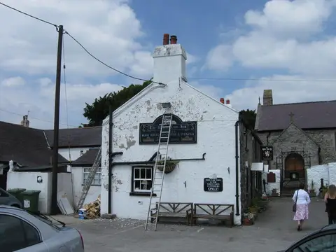 Whitewashed gable end of the White Lion Inn with its painted name board above the door