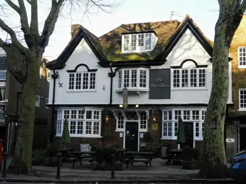 Symmetrical white pub with twin gables, leaded bay windows and a porch, between two plane trees