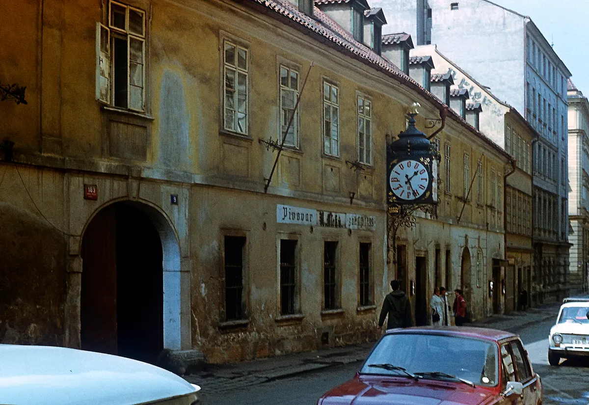U Fleku's street front in 1982, render stained and peeling, the brewery's iron clock hanging over the pavement
