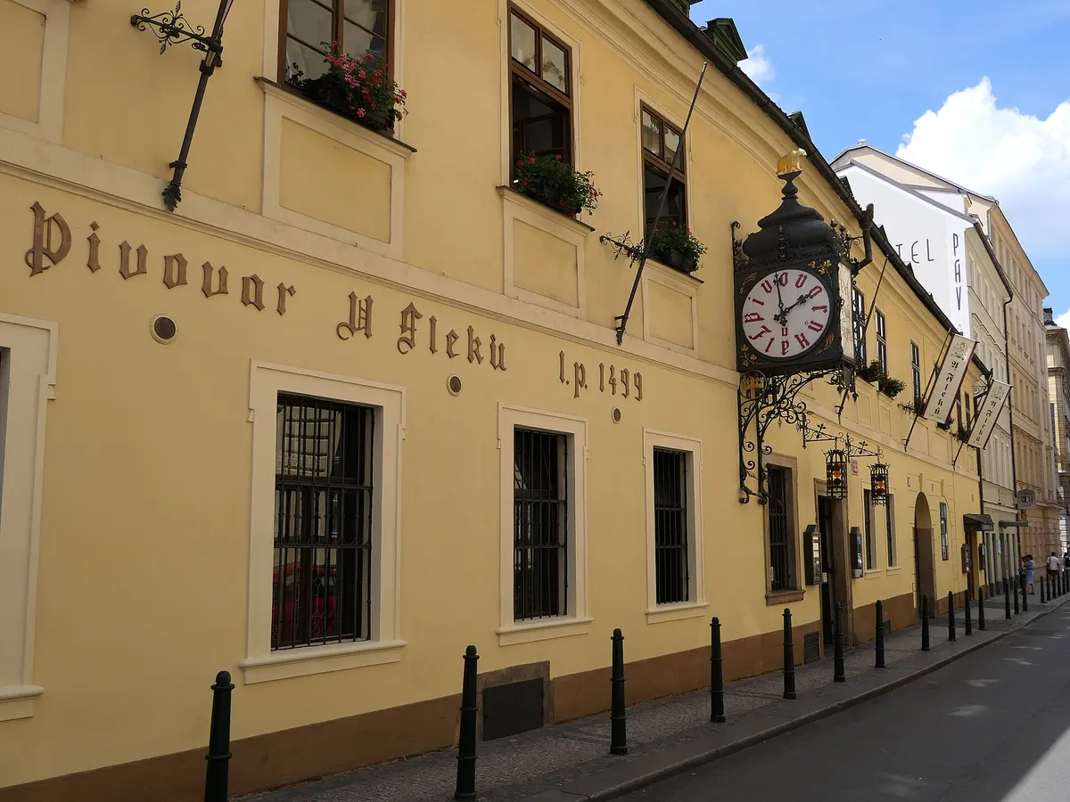 The long ochre front of U Fleku with gilt lettering reading Pivovar U Fleku l.p. 1499 and the iron clock