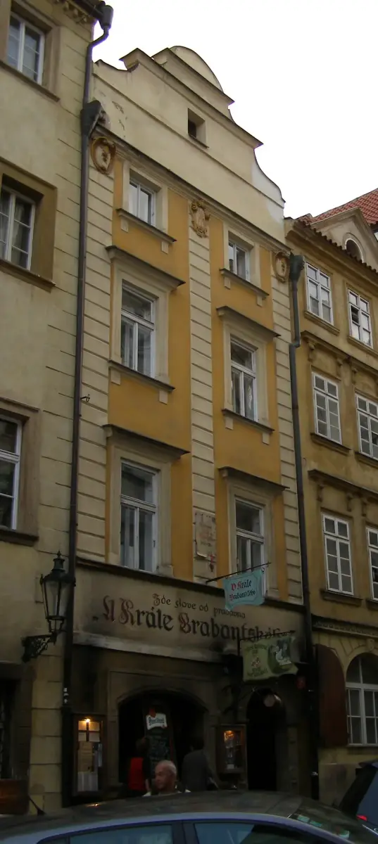 Tall yellow house in a Prague lane, the name painted in gothic letters across the ground floor