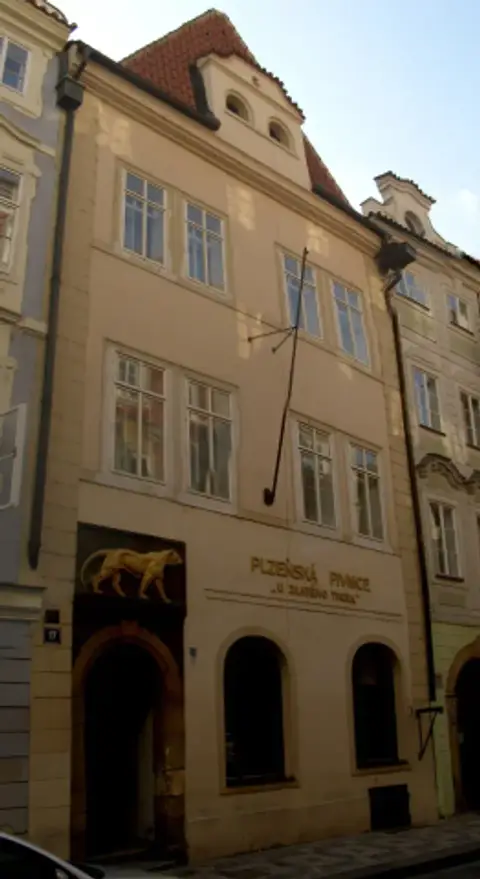 Narrow four-storey house with a red tiled roof, the tiger relief and pub lettering at street level