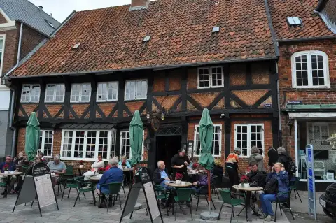 Half-timbered brick house on Torvet with a tiled roof and a busy pavement terrace in front