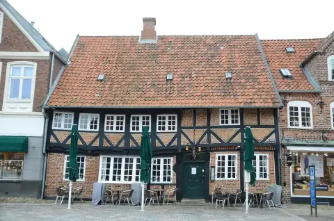 Half-timbered house with a sagging tiled roof, herringbone brick panels and a dark green door