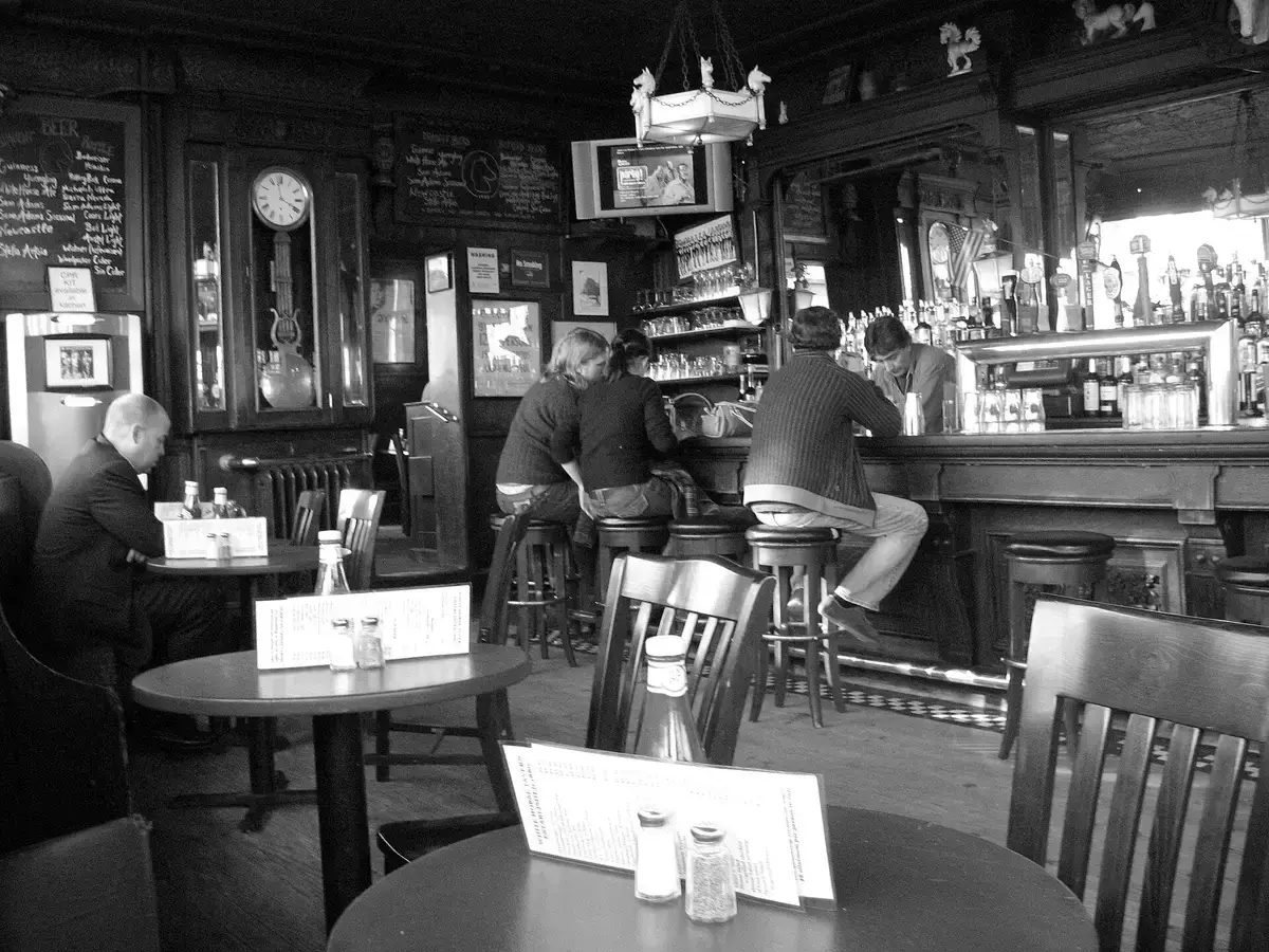 Dark timber bar with a long mahogany counter, tall clock, chalkboards and bentwood chairs
