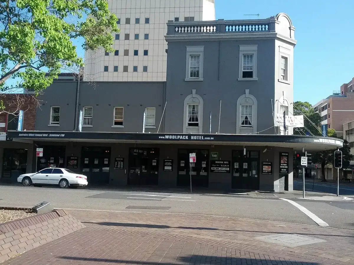 Grey rendered two-storey hotel with an awning over the footpath and arched upper windows