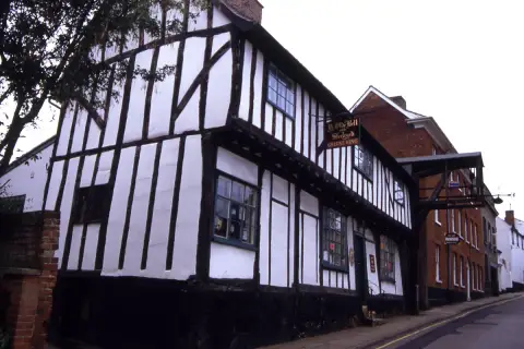 Close-studded timber-framed inn on a corner with a painted name board on an iron bracket